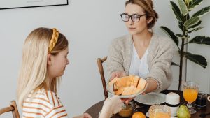 Mother and daughter enjoying a healthy breakfast together with fresh fruits and juice.